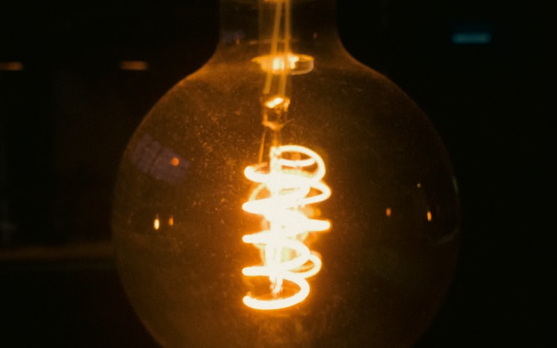 Close-up of a glowing tungsten bulb filament showing the coiled wire inside a clear glass bulb
