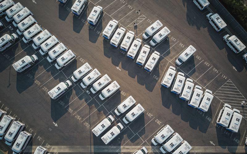Aerial view of a large fleet of white commercial vans parked in an organized transportation yard
